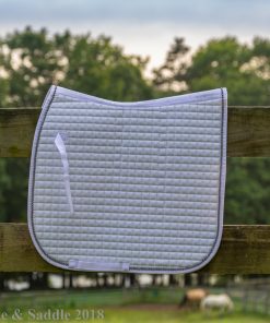 Horze Duchess dressage saddle pad in white hanging over fence